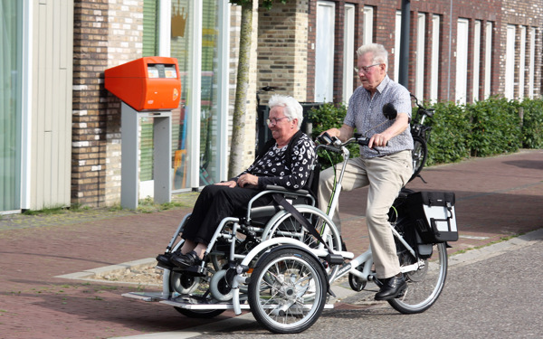 Man fiets met vrouw op de rolstoelfiets