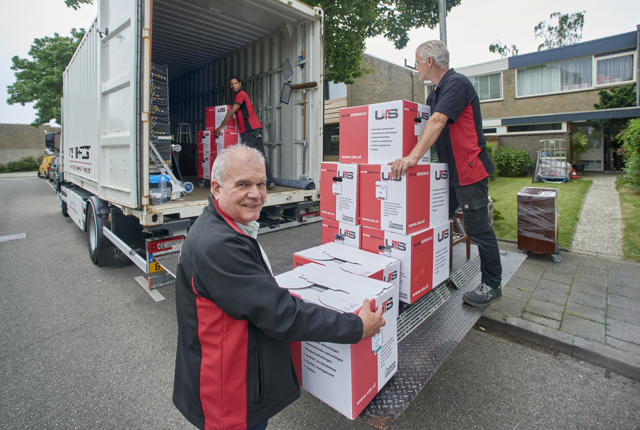 Verhuizers dragen verhuisdozen naar de verhuiswagen